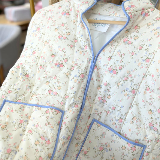 Floral quilted jacket with blue piping on a hanger