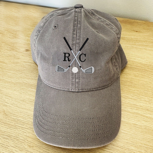 dark grey dad cap with a custom crossed golf club and 2 initial monogram embroidered design