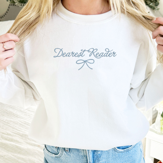 woman wearing a white crewneck with dearest reader and dainty bow embroidery