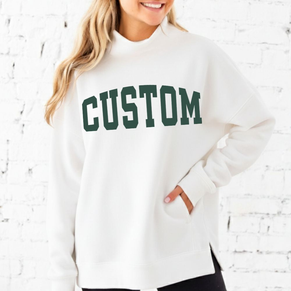 White sweatshirt with 'CUSTOM' printed in green on a white brick wall background