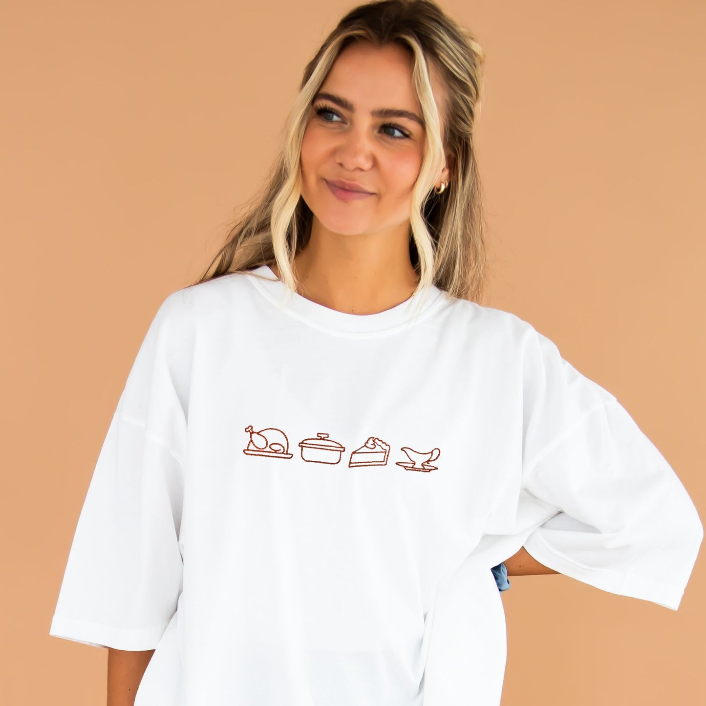 Young woman wearing a white comfort colors crewneck with custom thanksgiving embroidered icons