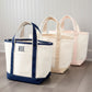 Three tote bags with different color combinations on a wooden floor.