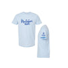 A light blue short-sleeve t-shirt shown from the front and side. The front features the text 'Montessori mom' in blue script, and the side view shows 'VMM' with a small cross printed on the sleeve.