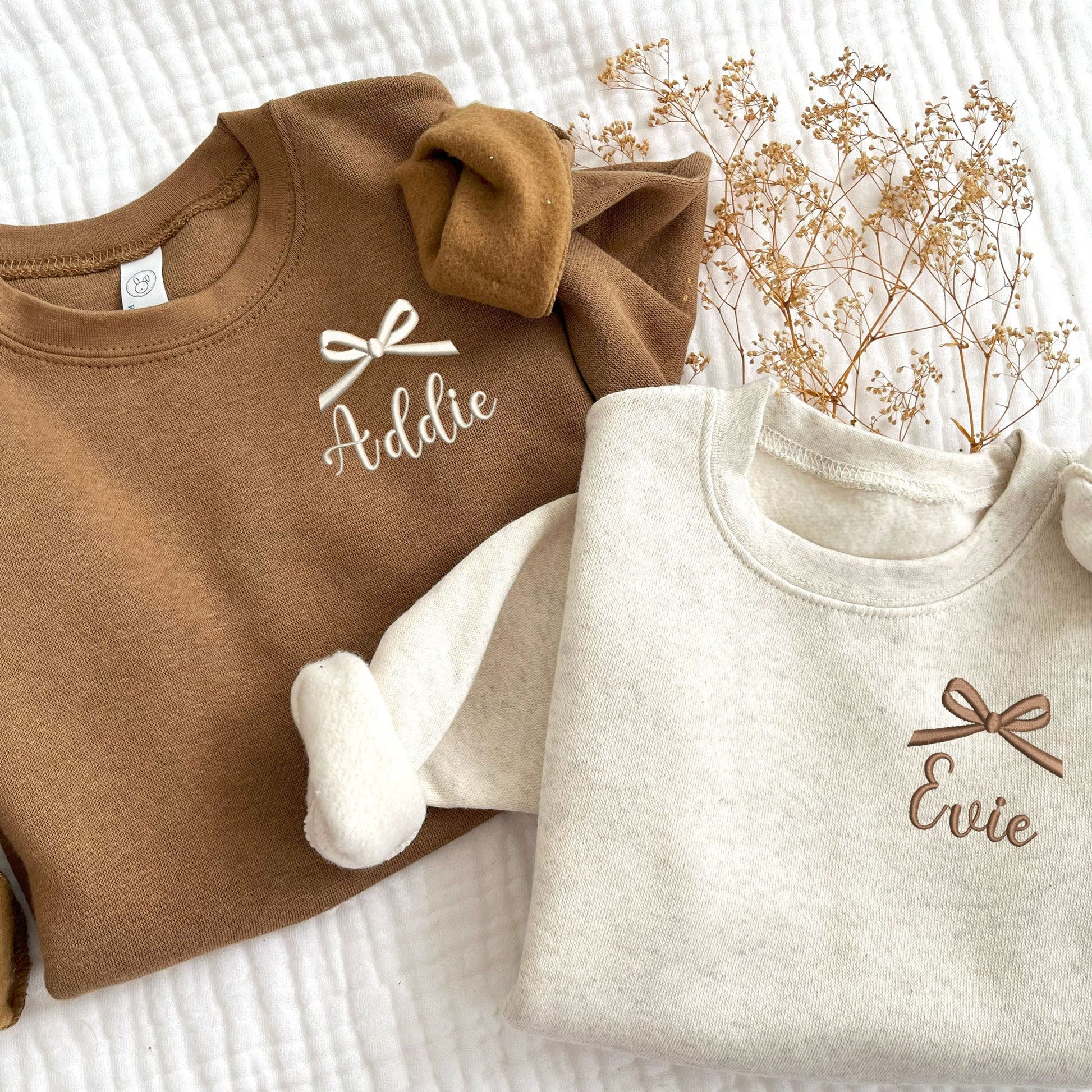 Coyote Brown toddler crewneck embroidered name and bow on the left chest in natural thread and natural heather toddler crewneck with embroidered name and bow on the left chest in Chestnut thread.