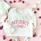 Christmas styled flat lay of a sweet cream crewneck with embroidered merry and bow design in pink thread