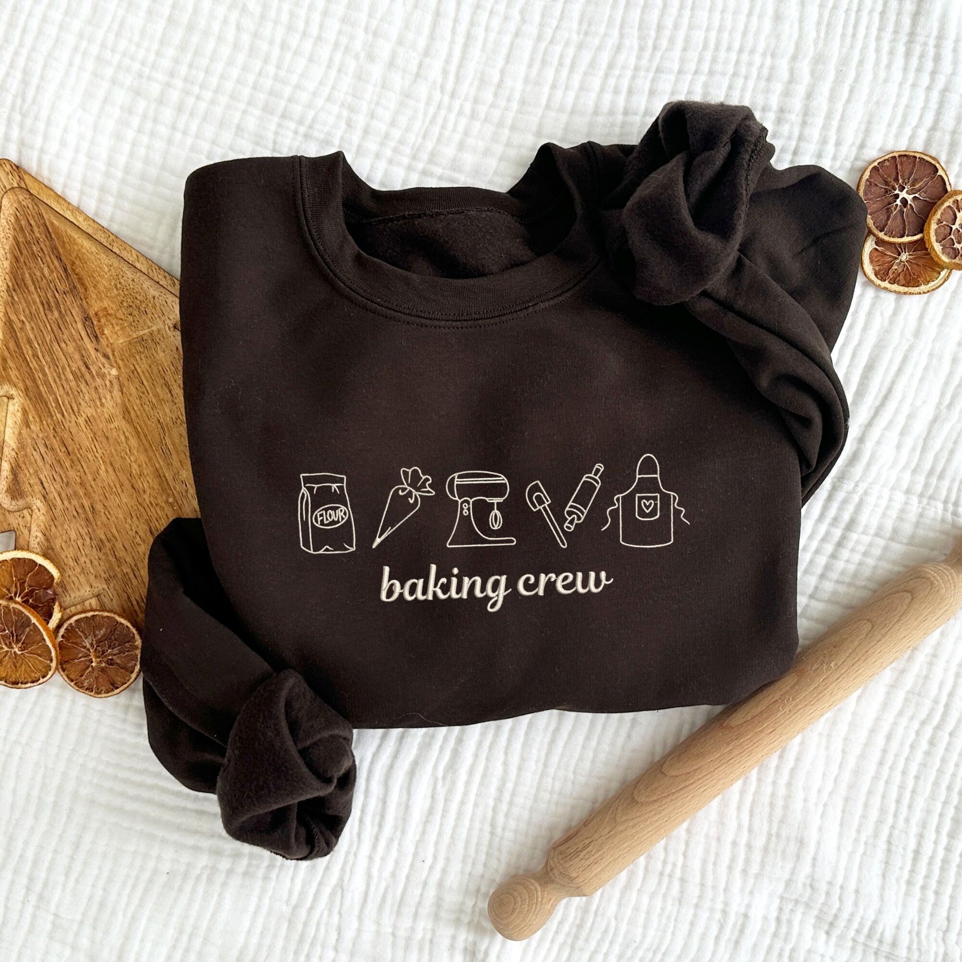 dark chocolate crewneck sweatshirt with embroidered outlined baking icons and baking crew text on the center chest in natural thread