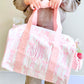 Person holding a pink floral tote bag with 'SWE' monogram on a light background