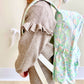 side view of a little girl wearing a pastel floral patterned backpack