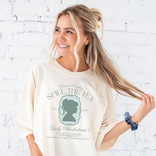 girl wearing an oversized ivory tee with a cute bridgerton inspired spill the tea lady whistledown printed design