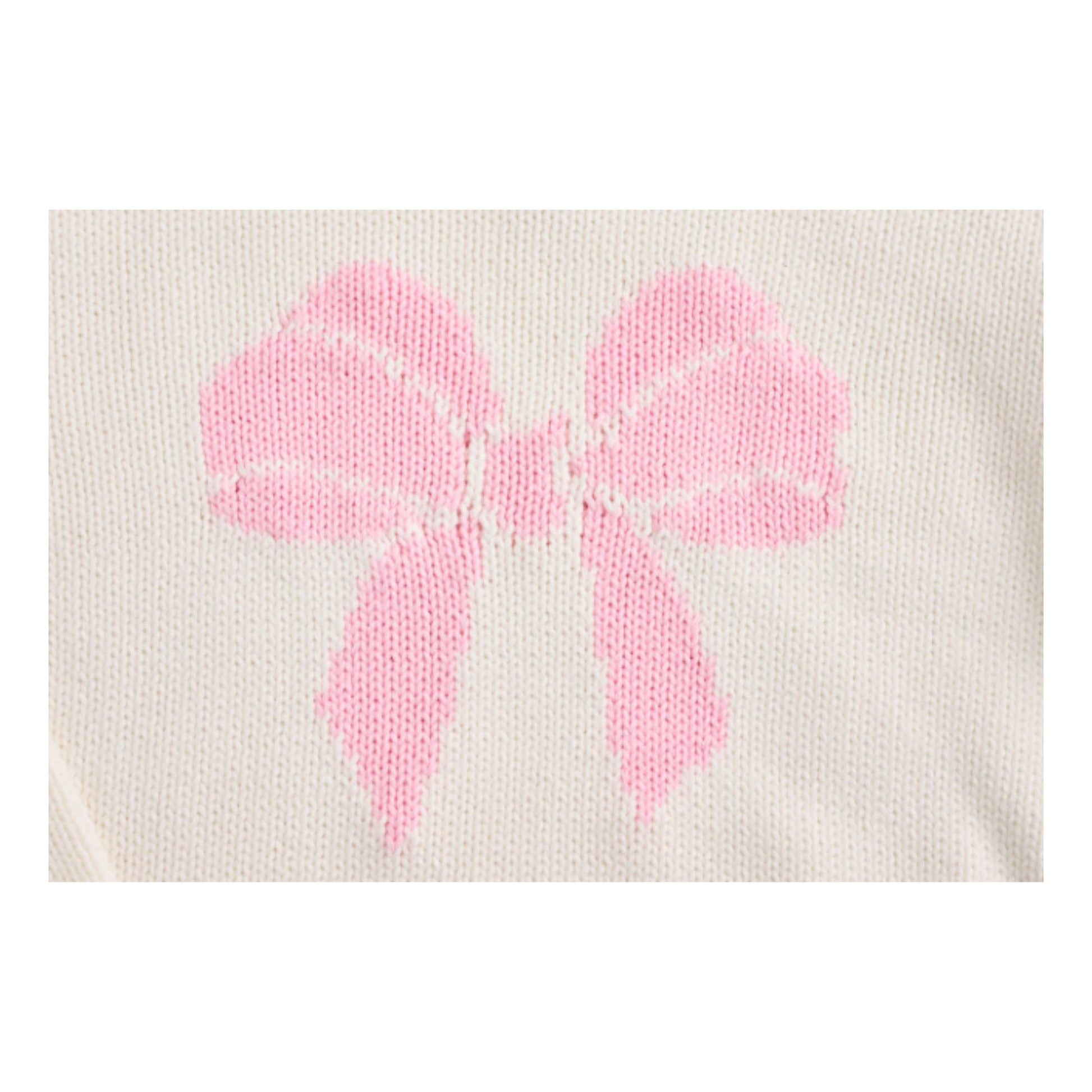 close up detail of pink bow stitched on a white sweater