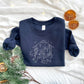 Christmas styled flat lay of a toddler navy crewneck with embroidered stitched nativity scene in white thread