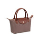 A small structured handbag in taupe with brown leather handles, trim, and front flap, plus a gold-tone snap button and zipper.