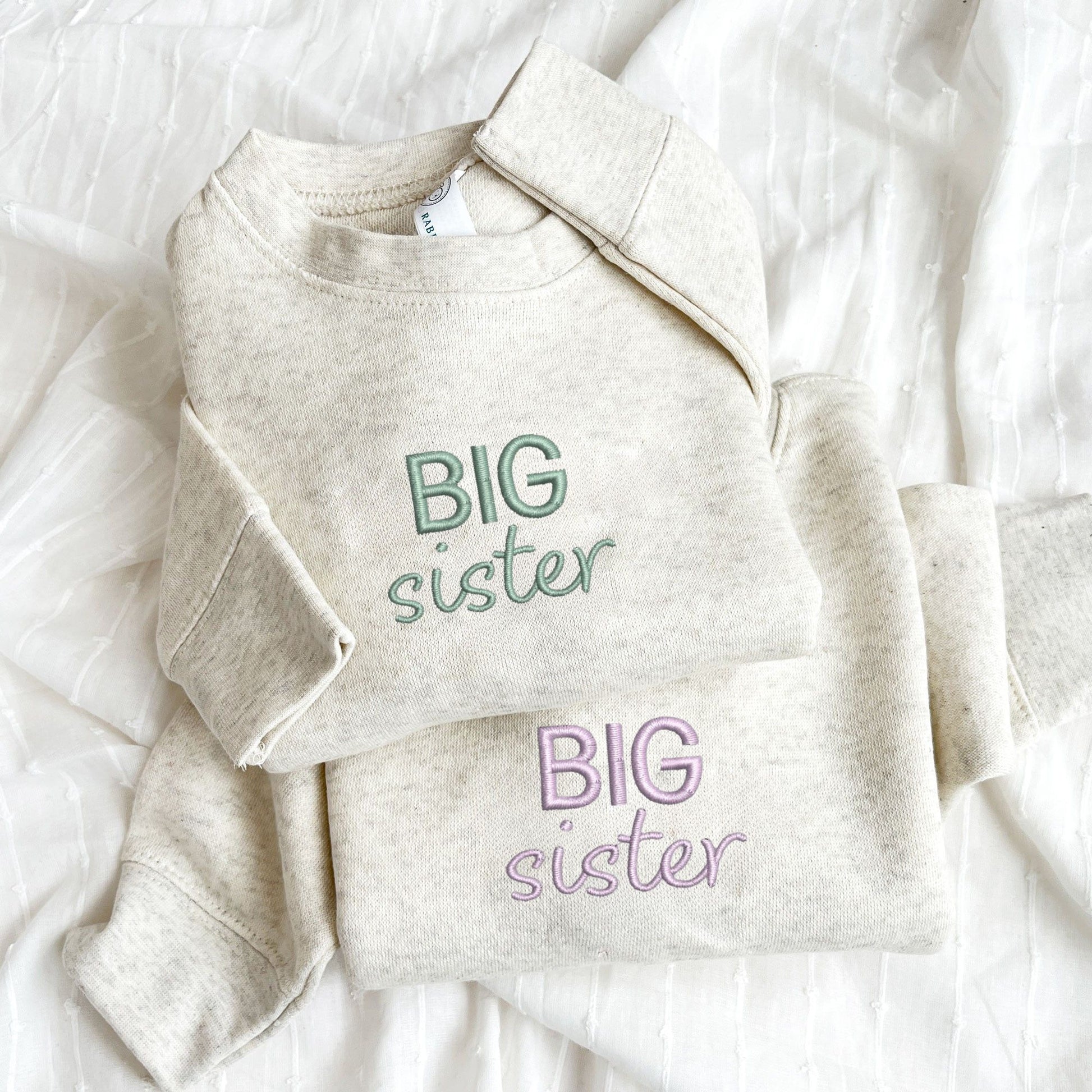 Natural Heather toddler crewnecks with custom BIG sister embroidered design on the center chest in eucalyptus and lilac thread