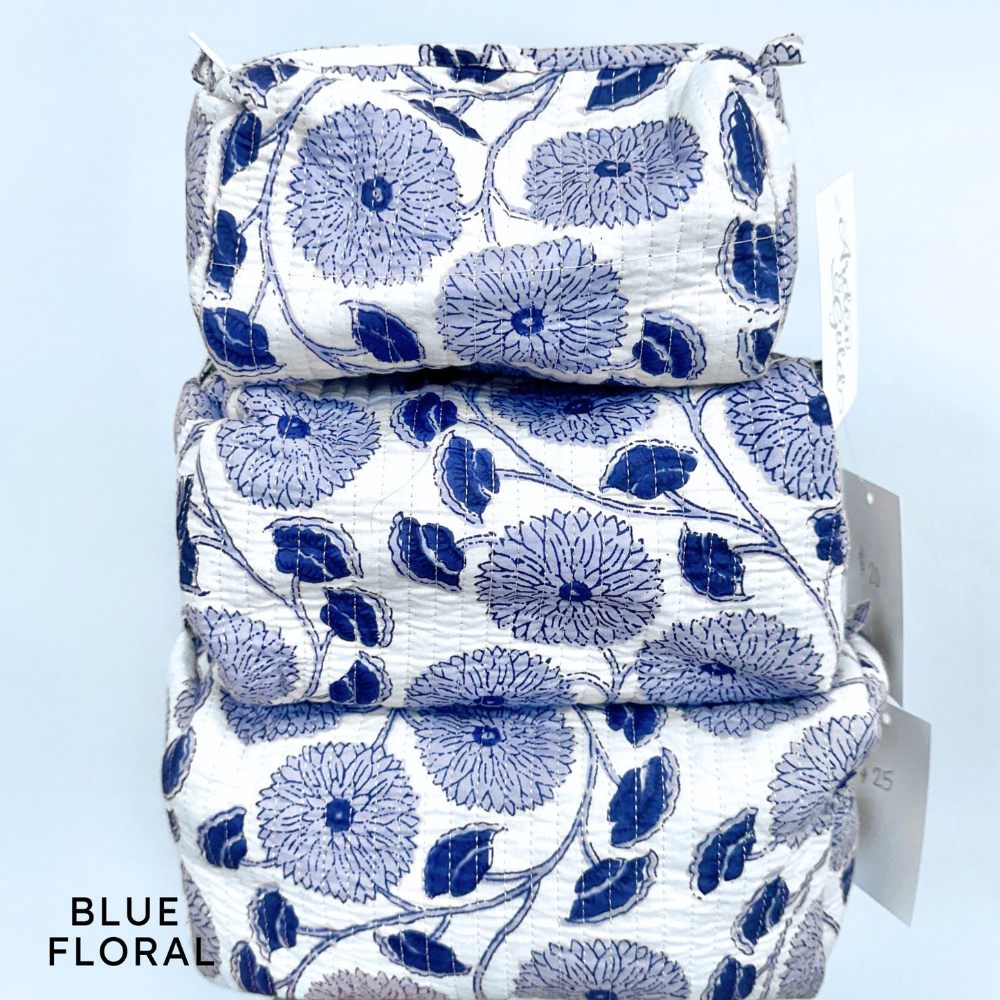 Stack of blue floral-patterned fabric pouches on a light blue background