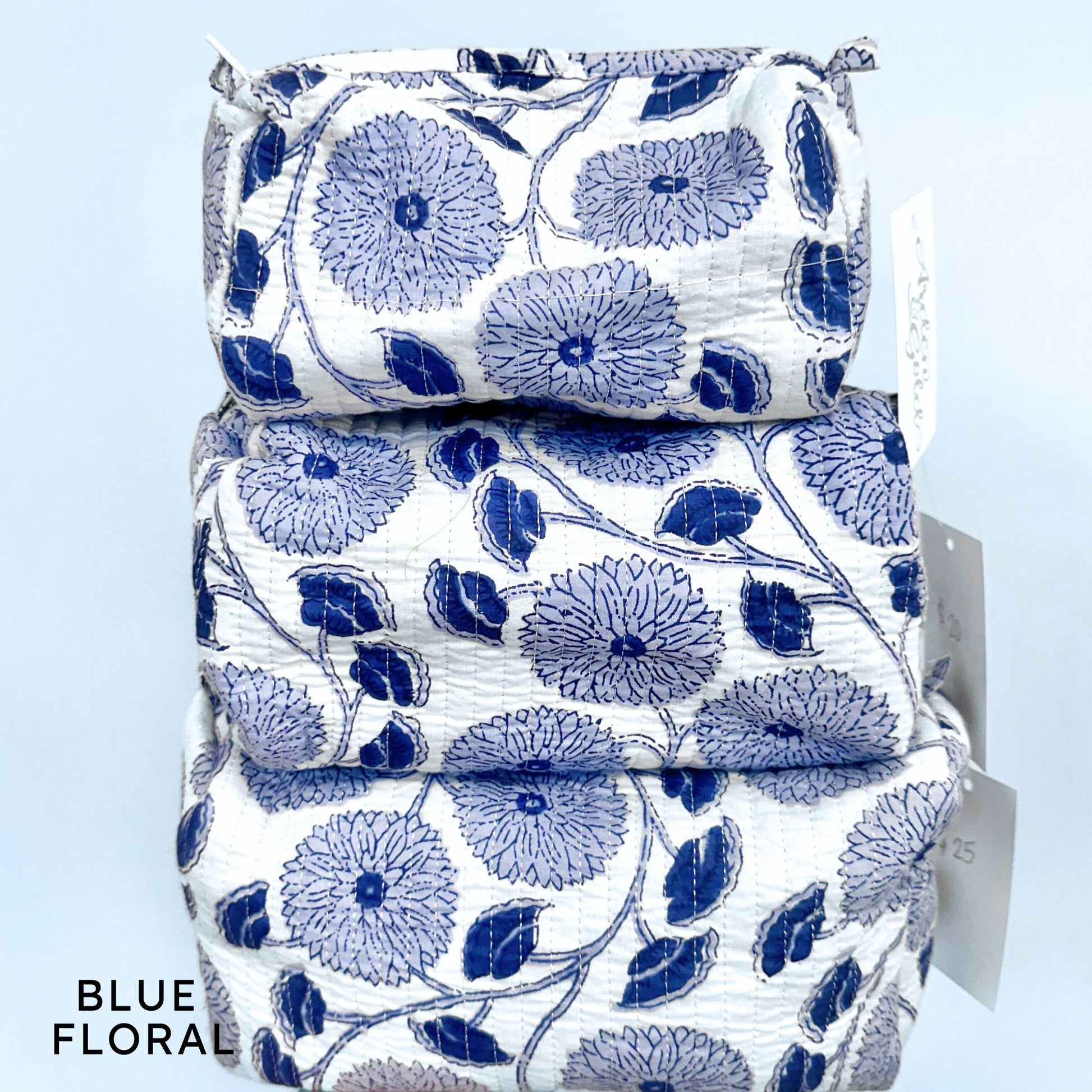 Stack of blue floral-patterned fabric pouches on a light blue background