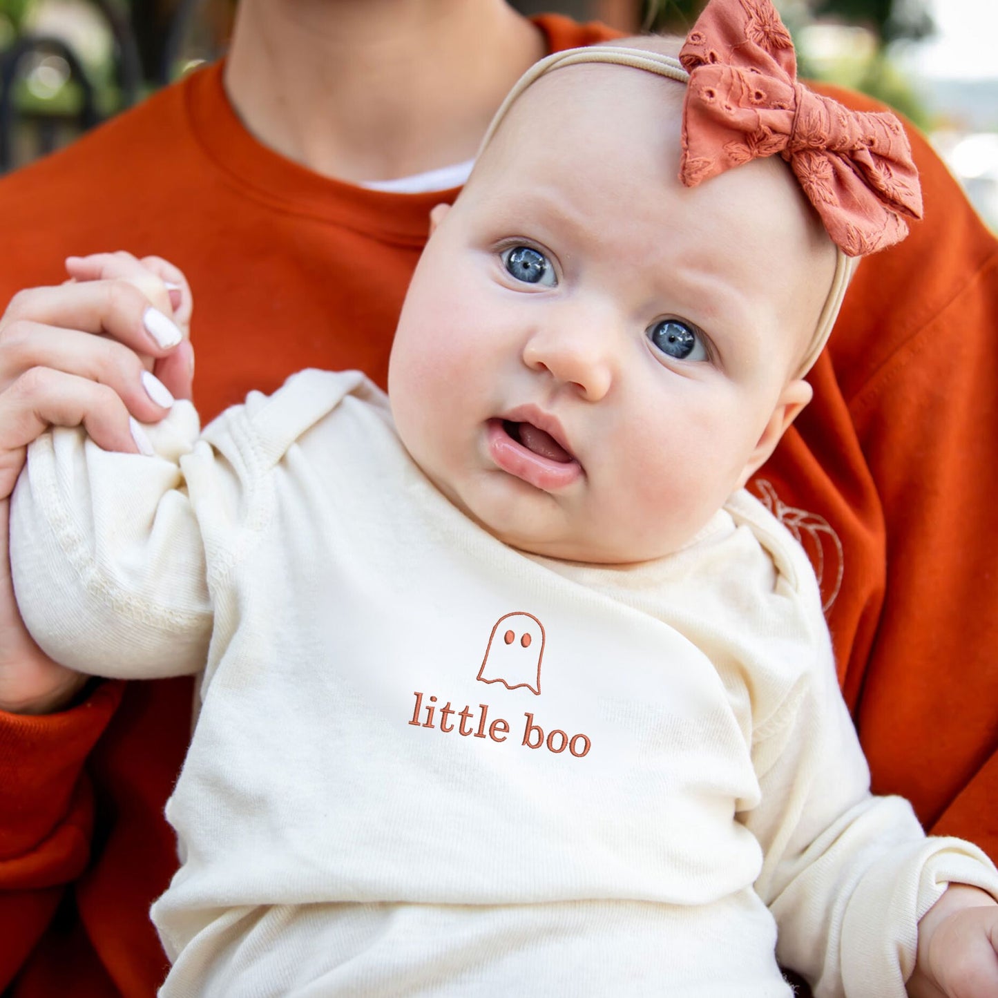 baby girl wearing a natural long sleeve bodysuit with custom cute ghost and little boo embroidered design