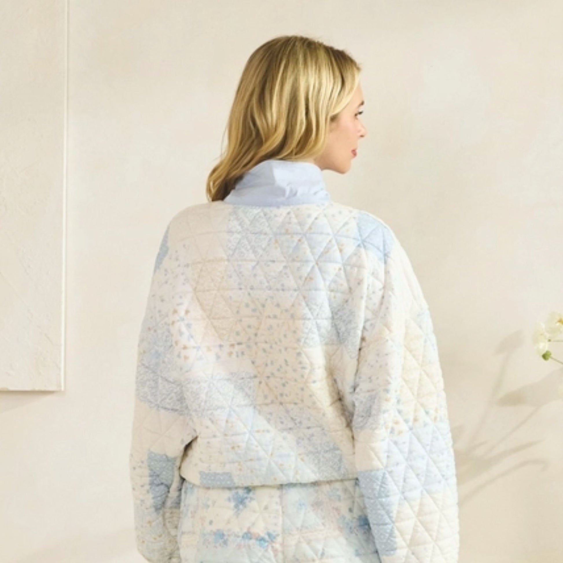 Woman wearing a light blue quilted jacket with a neutral background