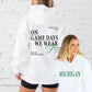 Two people wearing white hoodies with text on a white brick wall background