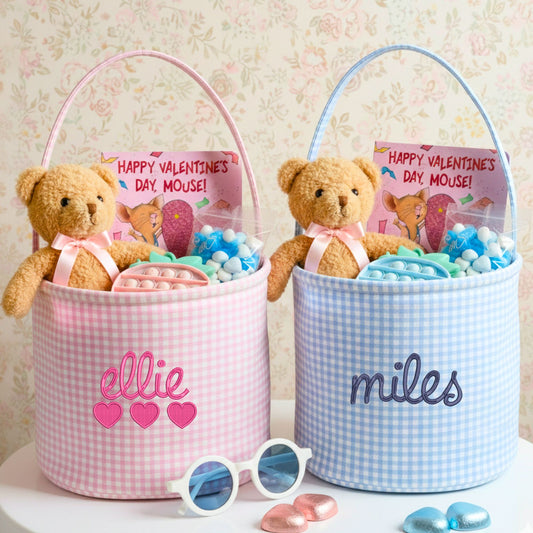 Two valentines baskets with custom name embroidery, stuffed with teddy bears, candies, and personalized cards on a floral background.