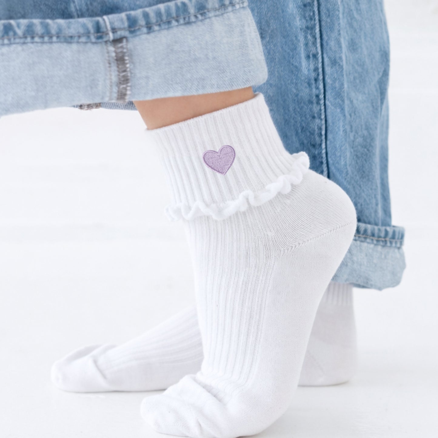 White socks with a purple heart design worn with light blue jeans.