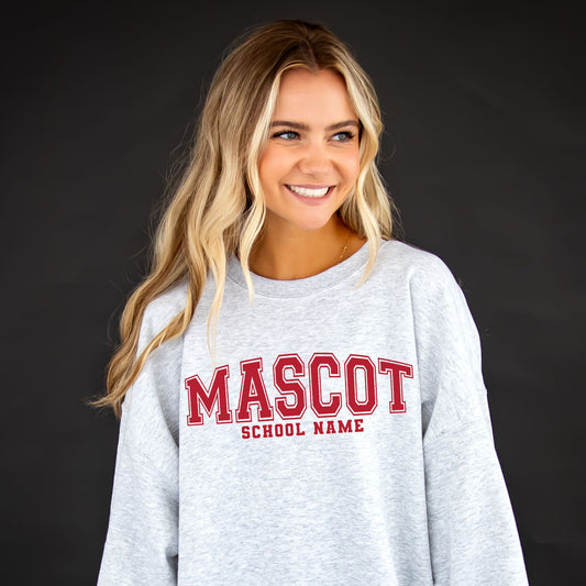 girl wearing an oversized ash crewneck sweatshirt with a custom school mascot varsity block printed design