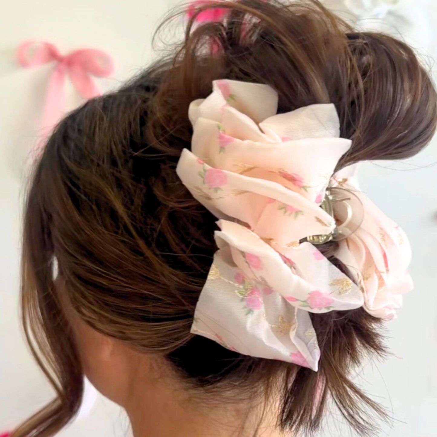 Floral claw clip on a ponytail with a pink ribbon in the background