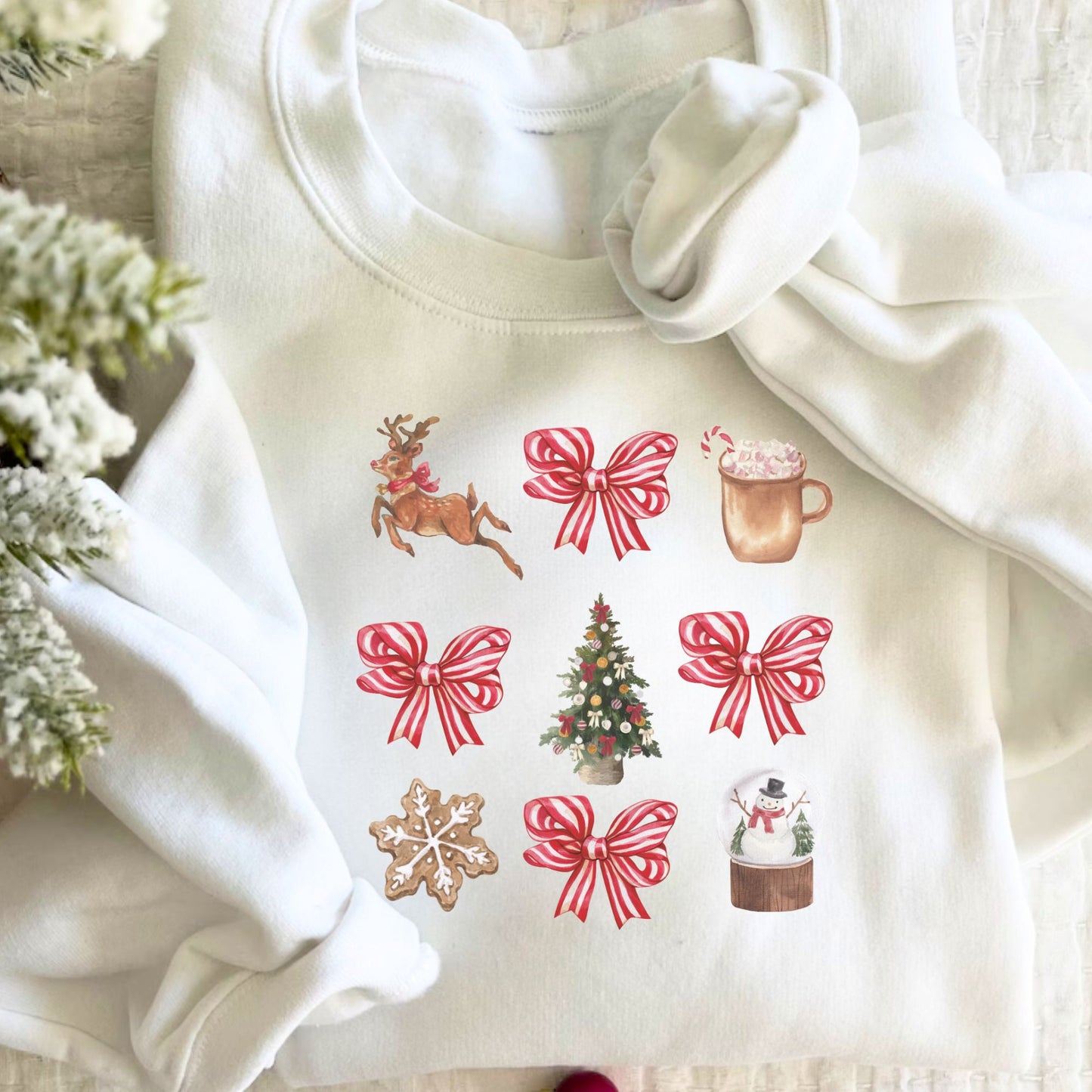 A white crewneck sweatshirt with a retro reindeer, bow, cocoa, tree, cookie, and snow globe printed design