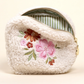 White fluffy pouch with floral embroidery on a beige background