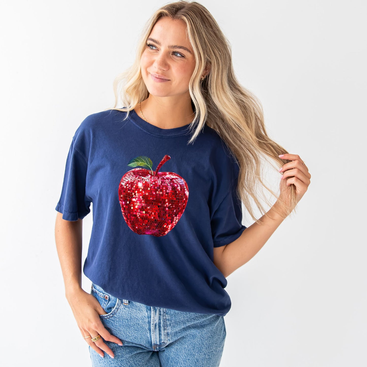 young woman wearing a true navy comfort colors t-shirt with large glitter apple print across the front of the chest