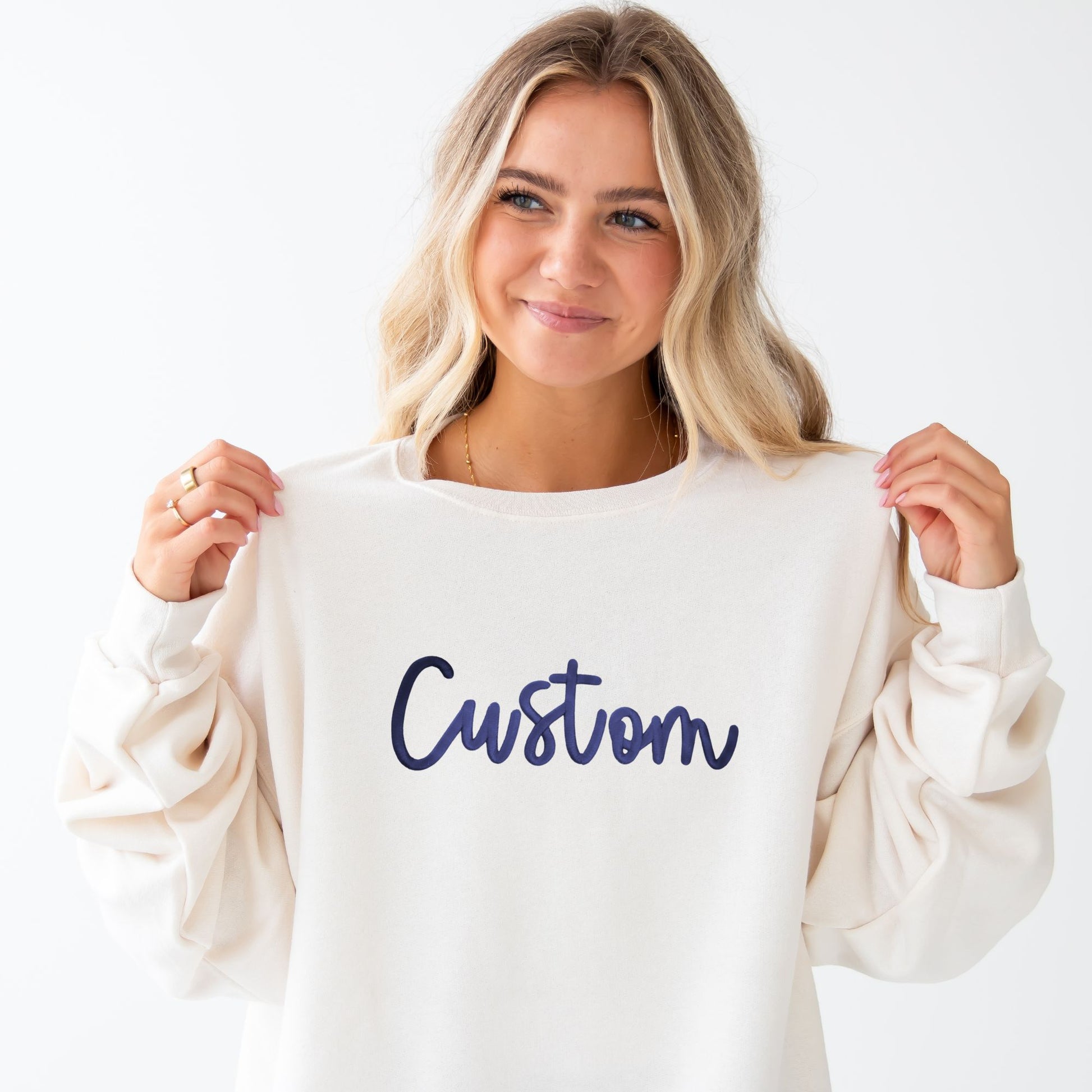 Woman holding a white sweatshirt with 'Custom' printed on it against a white background