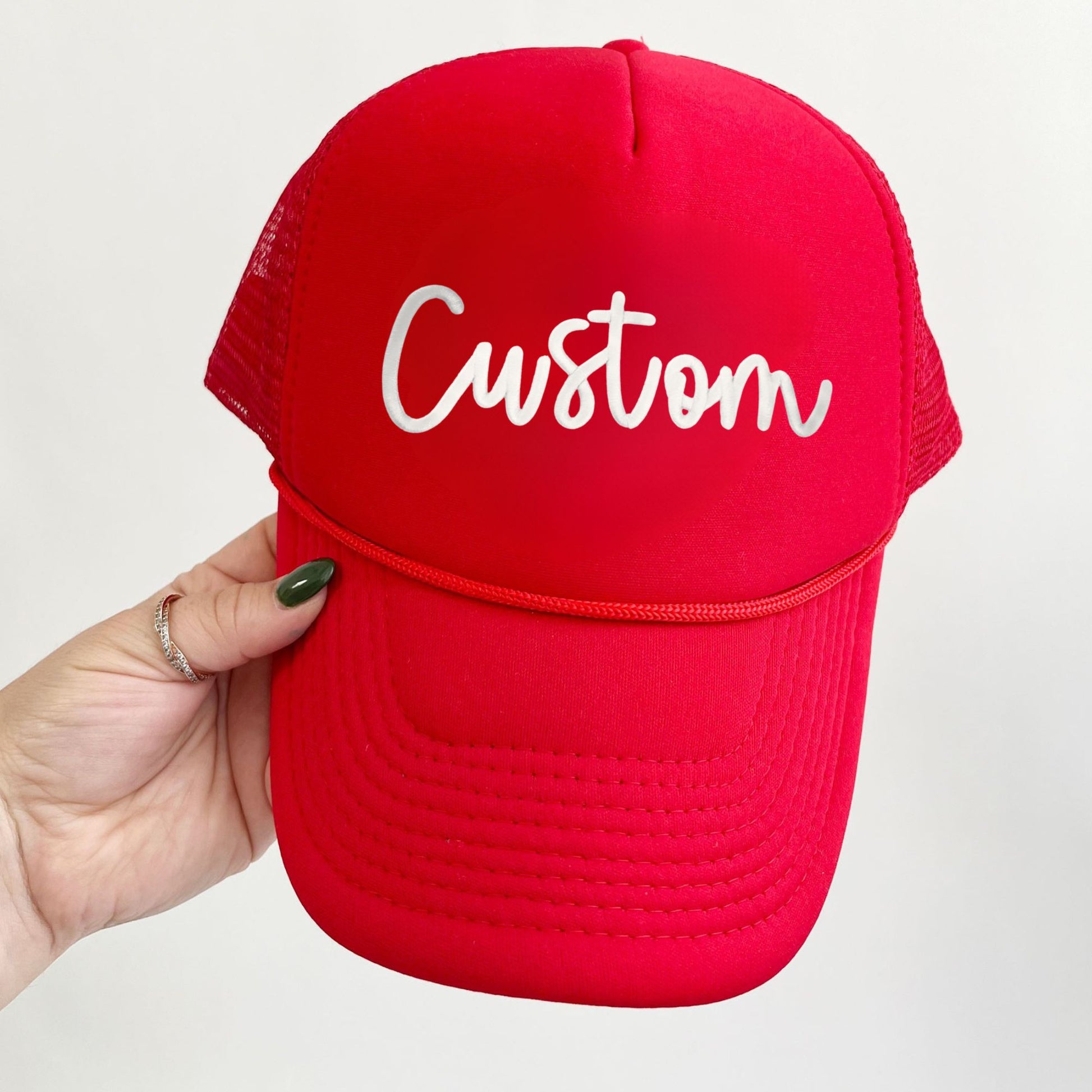 A red cap with 'Custom' embroidered in a 3d puff script font in white thread