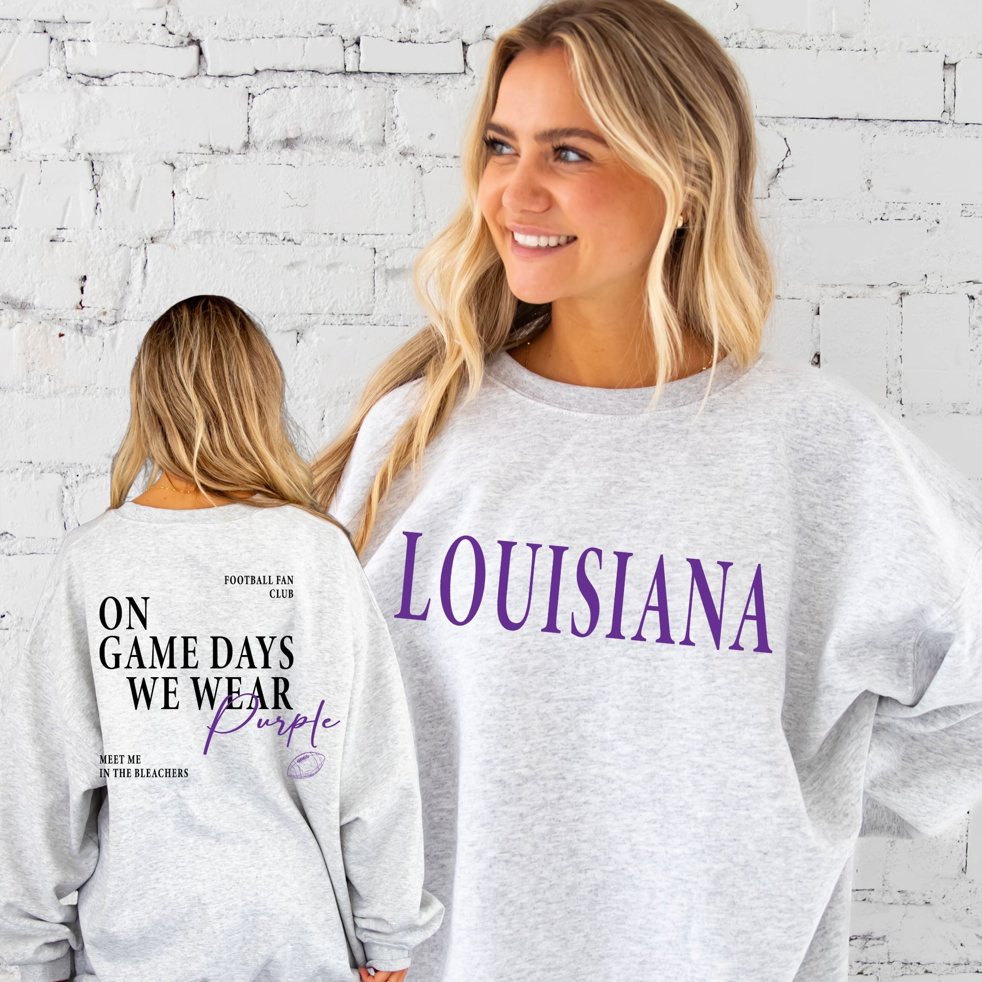 Two people wearing gray sweatshirts with 'LOUISIANA' and 'On Game Days We Wear Purple' text against a white brick wall.