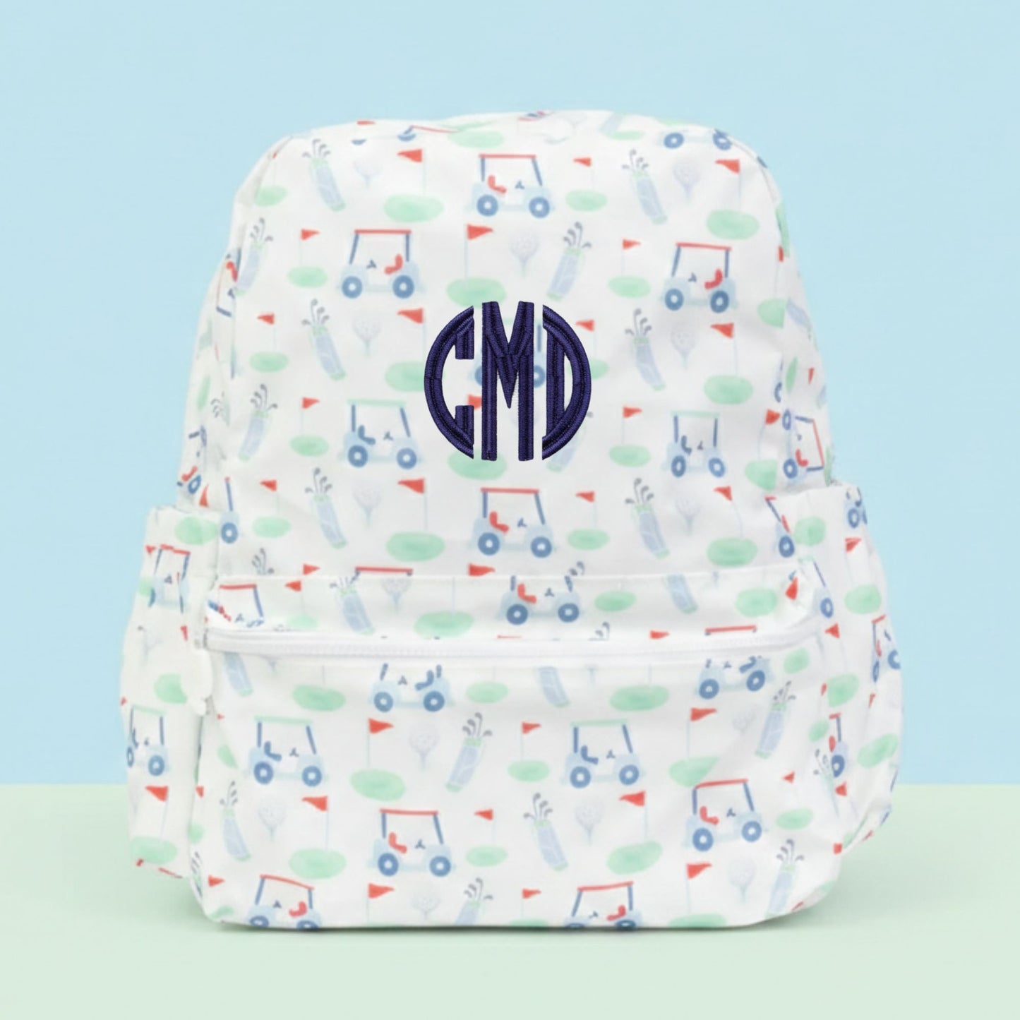 Backpack with golf pattern and a 'CMD' monogram on a light blue background