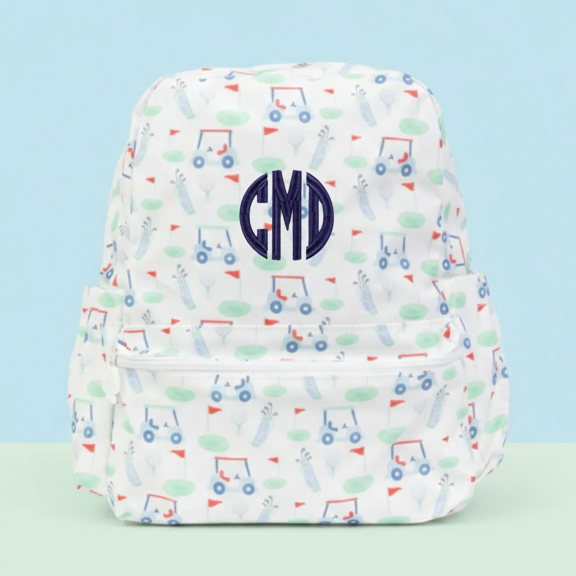 Backpack with golf pattern and a 'CMD' monogram on a light blue background