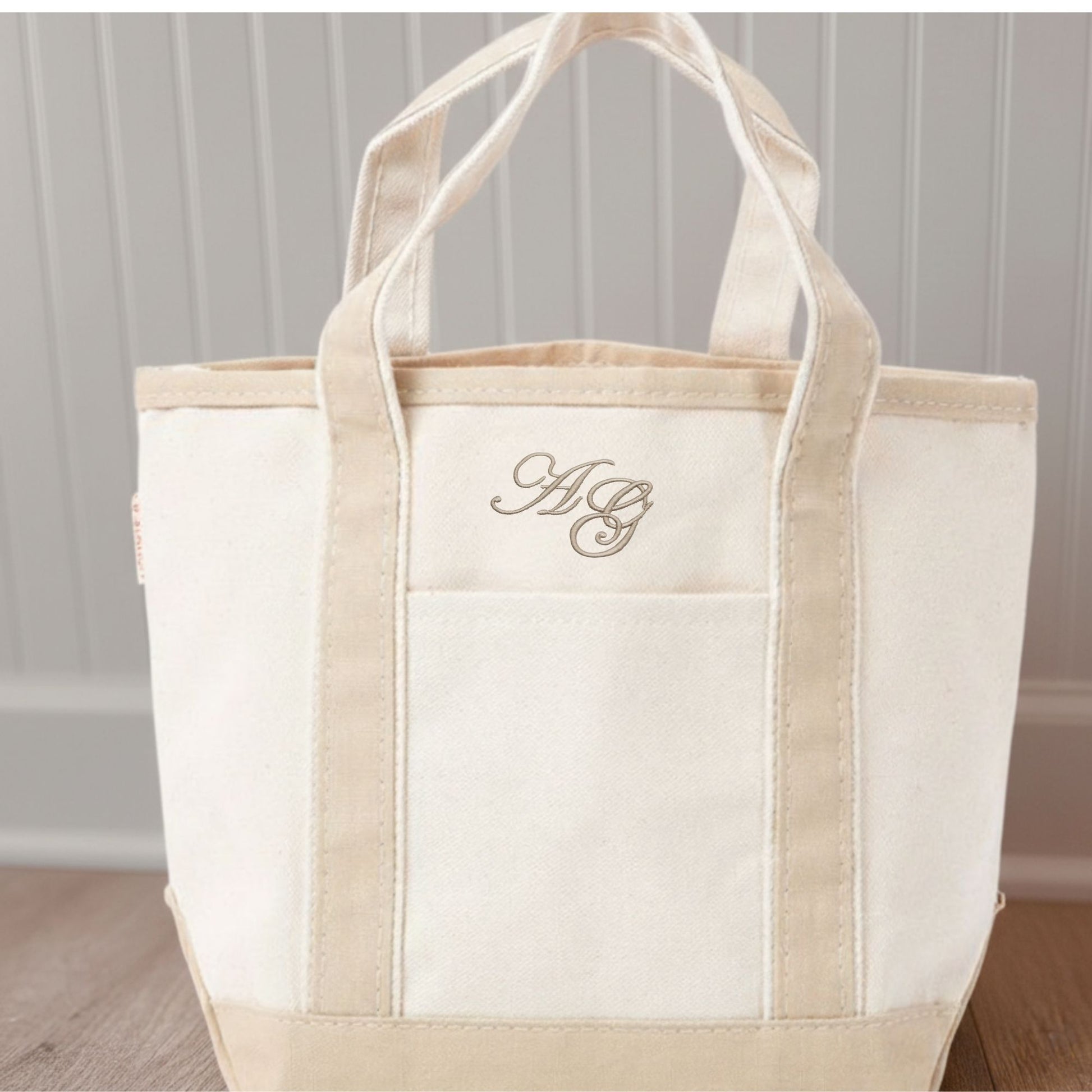 Beige tote bag with monogram on a wooden floor