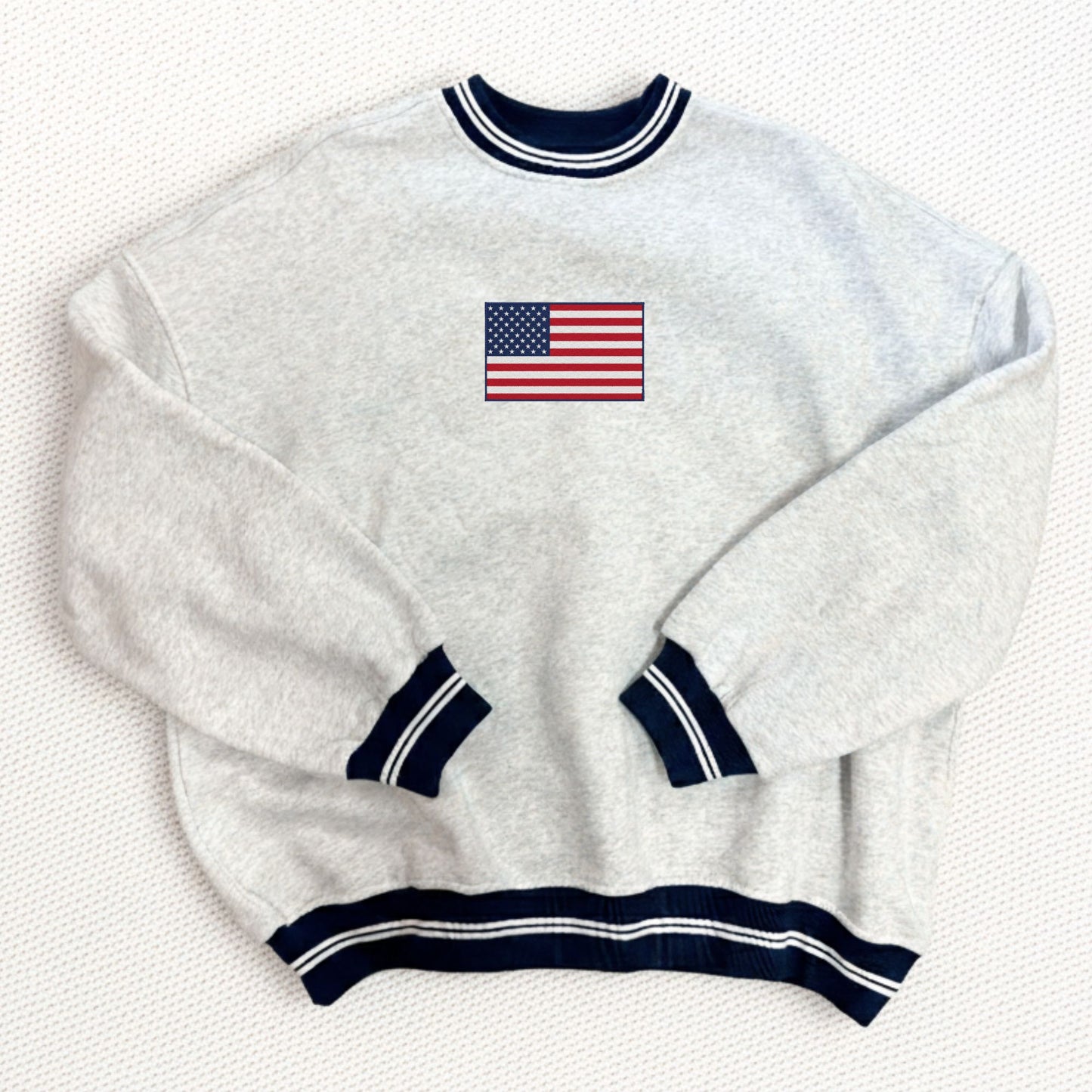 White sweater with American flag embroidery on a white background