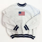 White sweater with American flag embroidery on a white background
