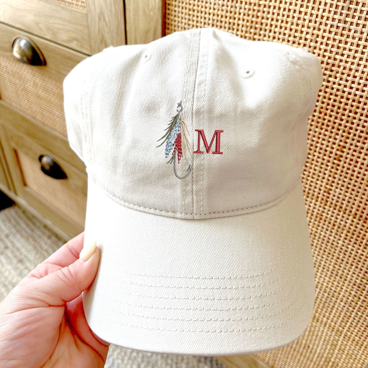 stone baseball cap with a fly fishing lure and single initial embroidered design on the center front