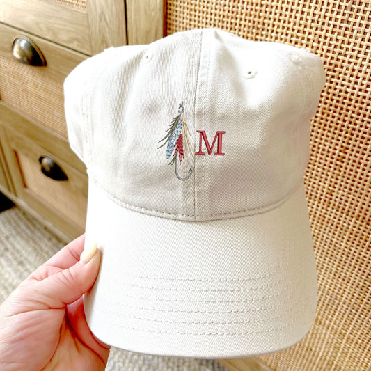 stone baseball cap with a fly fishing lure and single initial embroidered design on the center front