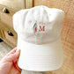 stone baseball cap with a fly fishing lure and single initial embroidered design on the center front