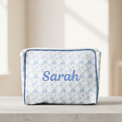 Floral-patterned pouch with 'Sarah' printed on it, placed on a surface.