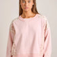 pink crew with floral lace sleeves worn by a person on a plain background