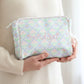 Person holding a pastel patterned pouch with 'Bridget' embroidered on it.