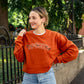  woman wearing a texas orange crewneck sweatshirt with embroidered SPOOKY and bats design in white and black threads