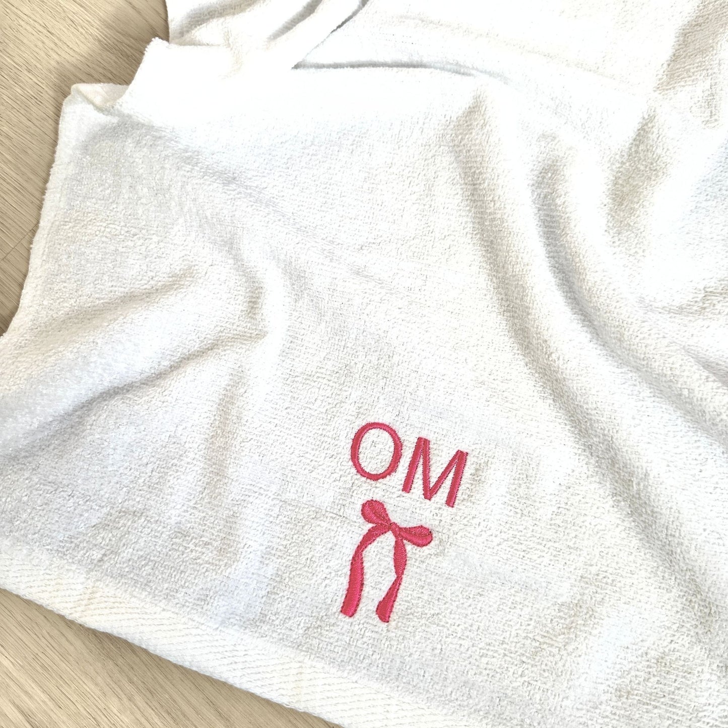 white gym hand towel with custom two letter and bow embroidered design in pink thread
