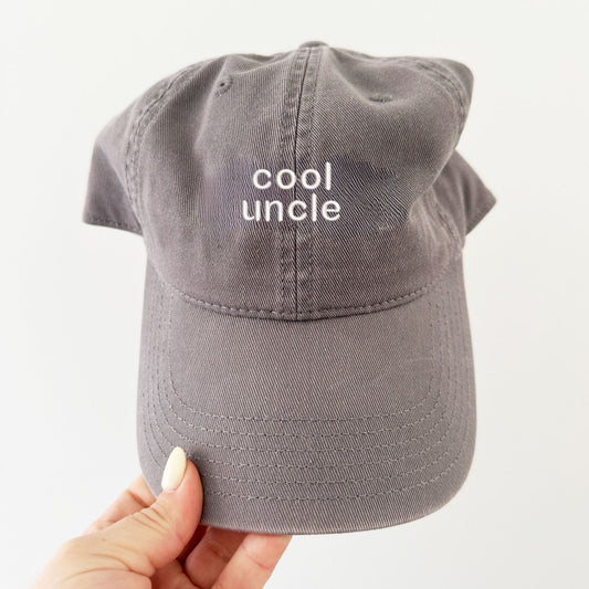 a gray baseball cap with cool uncle embroidered in a white thread