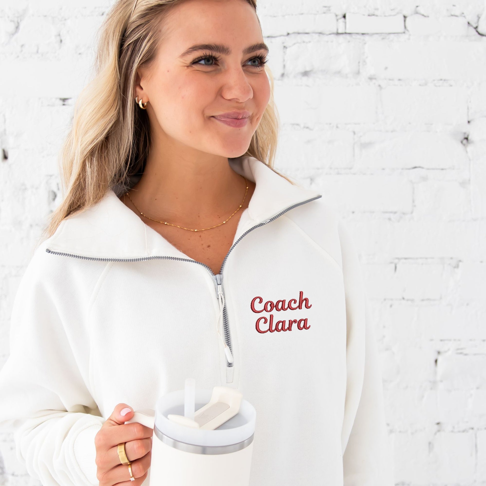 young woman wearing a sweet cream pullover boxy quarter zip with custom name embroidery