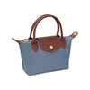 A small blue canvas handbag with brown leather handles, trim, and a front flap closure, shown on a plain white background.