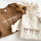 two toddler crewneck sweatshirts with embroidered 3 bows across the chest. the crewnecks are coyote brown with natural thread and natural heather crew with chestnut thread.