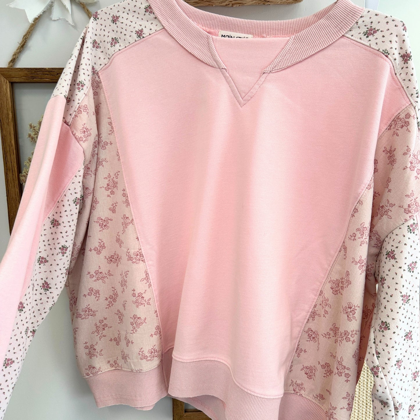 Pink sweatshirt with floral sleeves on a light background